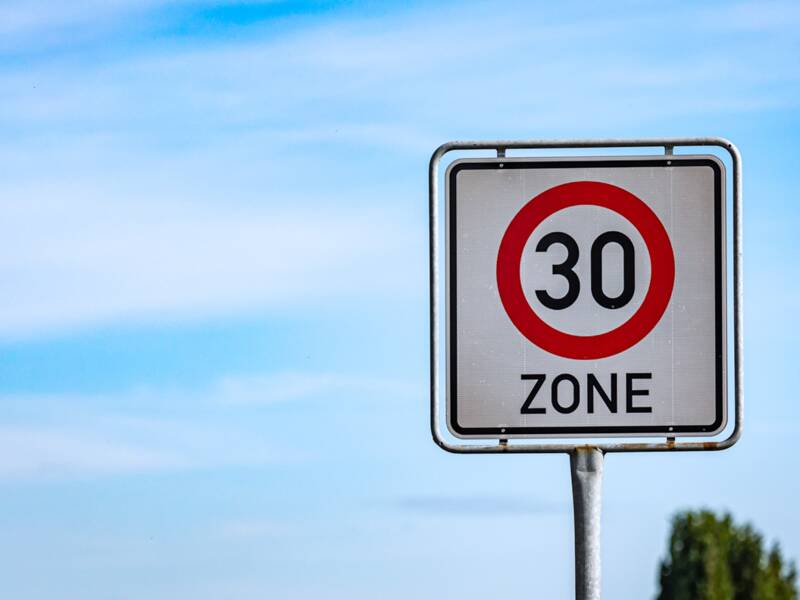 Ein Verkehrsschild, das auf den Beginn einer Tempo-30-Zone hinweist vor einem blauen Himmel.