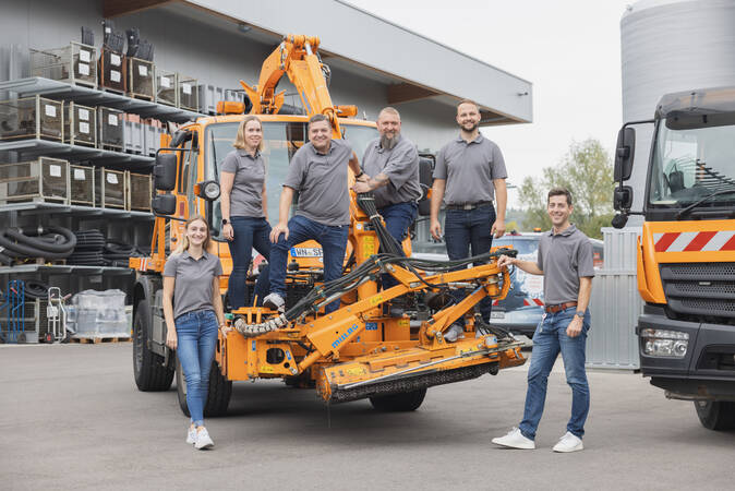 Gruppenfoto der Mitarbeiter der Verwaltung. Auf einem Fahrzeug stehend